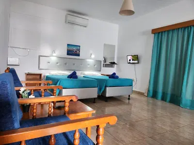 a hotel room with two beds and two benches at Florence Hotel Apartments in Ayia Napa