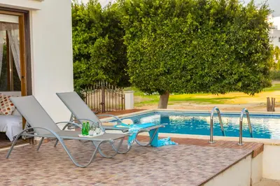 a pair of chairs and a table next to a swimming pool at Buena Vista Villa in Protaras