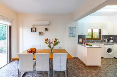 a kitchen with a dining room table and white chairs at Buena Vista Villa in Protaras