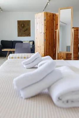 two white beds in a room with a couch at Art by PraXis in Governors Beach