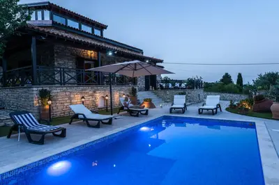 a swimming pool with chairs and an umbrella next to a house at Lefkara Villa in Kato Lefkara