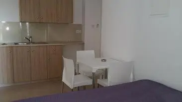 a kitchen with a table and two chairs and a kitchen with a sink at Simos Magic Hotel Apts in Ayia Napa