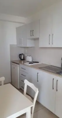 a kitchen with white cabinets and a white table and chair at Simos Magic Beach Hotel Apts in Ayia Napa
