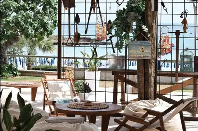 a patio with chairs and tables and a large window at Blue Peter Apartments in Protaras