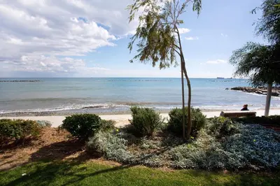 a person sitting on a bench next to the beach at Opera Exclusive Apts by TrulyCyprus in Limassol