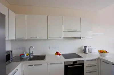 a white kitchen with white cabinets and a sink at Opera Exclusive Apts by TrulyCyprus in Limassol