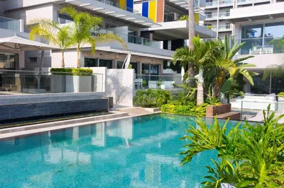 a swimming pool in front of a building with palm trees at Opera Exclusive Apts by TrulyCyprus in Limassol