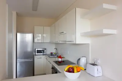 a kitchen with white cabinets and a bowl of fruit at Opera Exclusive Apts by TrulyCyprus in Limassol