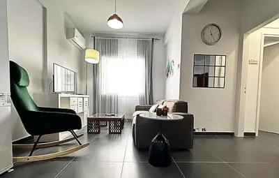 a living room with a chair a couch and a clock at Home Away One Bedroom Apartment in Nicosia in Nicosia