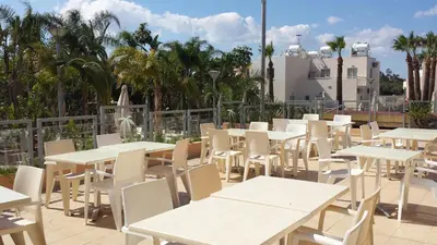 a row of tables and white tables and chairs at La Casa Di Napa Apartments in Ayia Napa