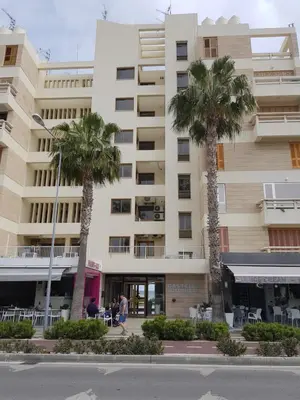 a large building with palm trees in front of it at Haig's Dream Flat On The Beach in Larnaka