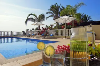a table with fruit and a pitcher of juice next to a pool at Villa Cleopatra in Ayia Napa