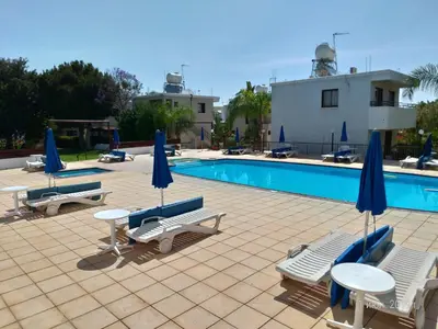 a pool with chairs and tables and umbrellas at Maricosta Apartments in Protaras