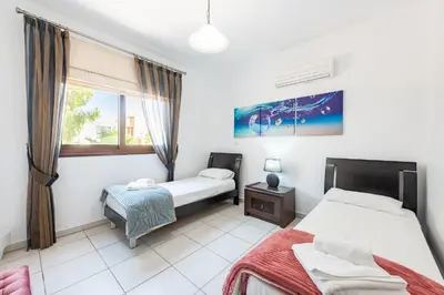 a bedroom with two beds and a window at Sea Front Oceanus H3 by Ezoria Villas in Ayia Napa