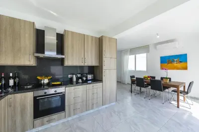 a kitchen with wooden cabinets and a dining table at Protaras Villa Araella in Ayia Napa
