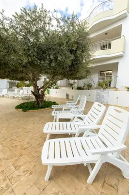 a row of white lounge chairs in front of a building at Oceania Bay Village in Pyla