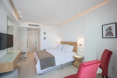 a hotel room with a bed and a desk and a tv at Kokkinos Boutique Hotel in Protaras