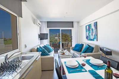 a kitchen and living room with a sink and a table at Nicholas Seaview Apartments in Protaras