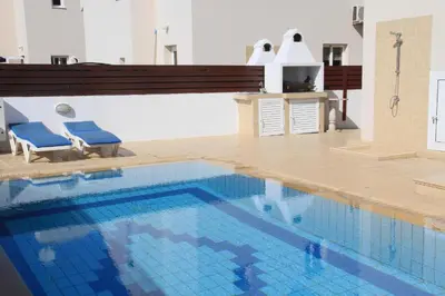 a large swimming pool with two blue chairs next to it at Maricosta Villas in Protaras