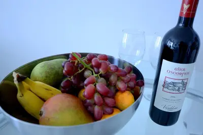 a bowl of fruit next to a bottle of wine at Blue Dawn Center Flat in Larnaka
