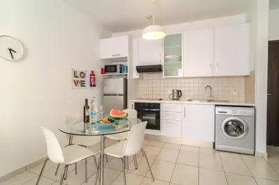 a kitchen with a glass table and white cabinets at Violet Dusk City Center Flat in Larnaka