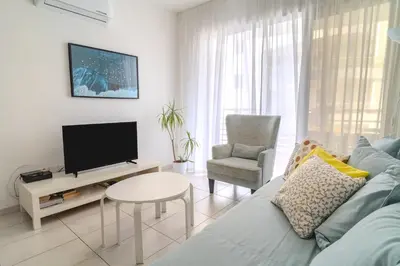 a living room with a couch and a tv and a chair at Violet Dusk City Center Flat in Larnaka