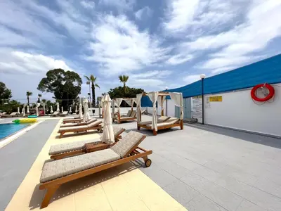 a row of chaise lounges next to a swimming pool at Adelais Bay Hotel in Protaras