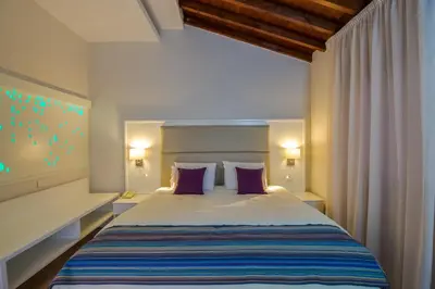 a bedroom with a large bed with purple pillows at MyroAndrou Beach Hotel Apartments in Protaras