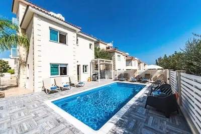 a swimming pool in front of a house at Timotheos Villa in Protaras