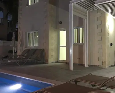 a house with a swimming pool at night at Timotheos Villa in Protaras