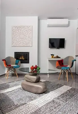 a living room with two chairs and a fireplace at Mesogios House Suites in Larnaka