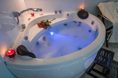 a jacuzzi tub in a bathroom with a candle at Mesogios House Suites in Larnaka