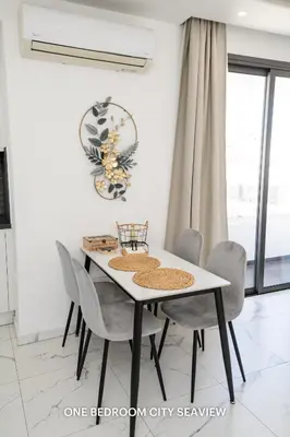 a dining room with a white table and chairs at Lazuli Seaview Apartments 2Bdr in Larnaka