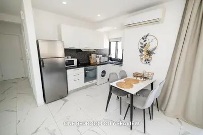 a kitchen with a table with chairs and a refrigerator at Lazuli Seaview Apartments 2Bdr in Larnaka