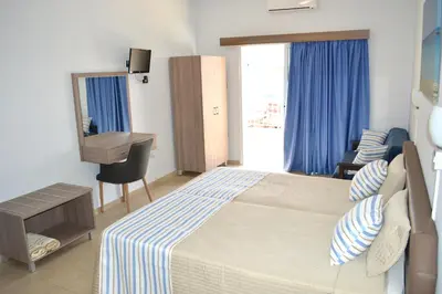 a bedroom with a bed and a desk and a mirror at Millie's Apartments in Ayia Napa