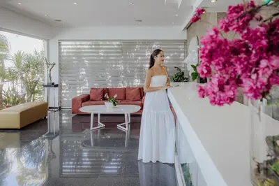 a woman in a white dress standing in a living room at Tasia Maris Oasis in Ayia Napa