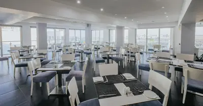 a restaurant with tables and chairs and windows at Tasia Maris Oasis in Ayia Napa