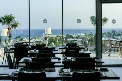 a restaurant with tables and chairs and a view of the ocean at Eleana Hotel in Ayia Napa