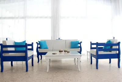 a living room with blue and white chairs and a table at Flokkas Hotel Apartments in Protaras