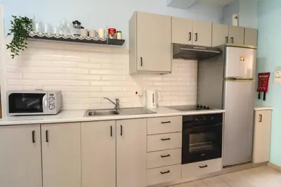 a kitchen with white cabinets and a stainless steel refrigerator at Helios Mackenzie One Bedroom Flat in Larnaka