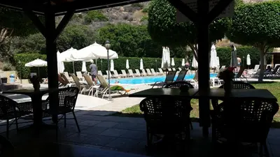 a patio with tables and chairs next to a pool at Kotzias Beach Apartments in Pissouri