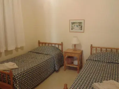 a bedroom with two beds and a table with a lamp at Pelekanos Apartments in Pissouri