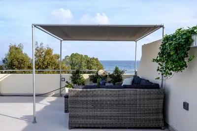 a patio with wicker furniture and a view of the ocean at The Coral Penthouse in Larnaka