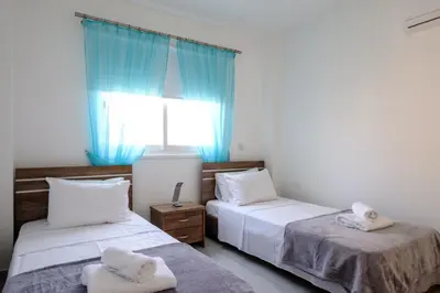 a bedroom with two beds and a window with blue curtains at The Coral Penthouse in Larnaka