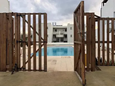 a wooden gate leading to a pool in a building at Ayia Napa GO SEA Sunny Apt with Terrace 5 min to Beach in Ayia Napa