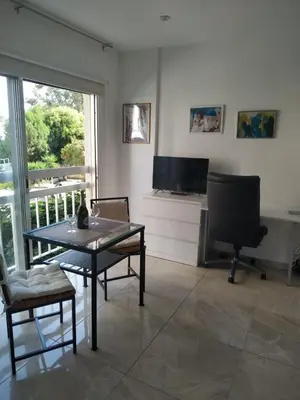 a living room with a table and a television at Stelia's Seagate Studio Apt. in Larnaka