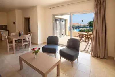 a living room with a table and chairs and a balcony at Makronisos Village in Ayia Napa