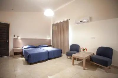 a bedroom with a bed and two chairs and a table at Makronisos Village in Ayia Napa