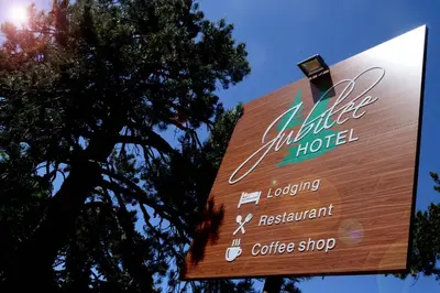 a sign for a hotel with a tree in the background at Jubilee Hotel Troodos in Troodos