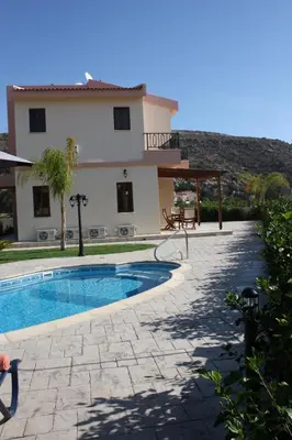 a villa with a swimming pool in front of a house at Holidays Villas in Pissouri